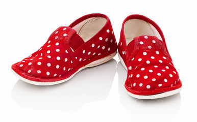 Children´s red spotted slippers isolated on the white background. Kid´s red slippers with white spots. Comfortable slippers isolated on the white background with shadow reflection.