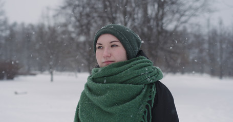 girl standing in park on winter day under snowfall