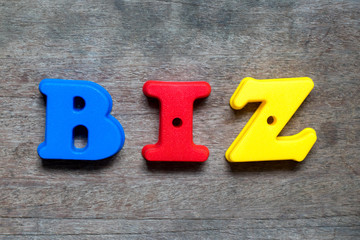 Color alphabet in word biz (abbreviation of business) on wood background