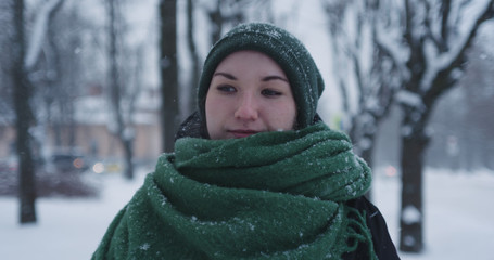 girl standing in park on winter day under snowfall