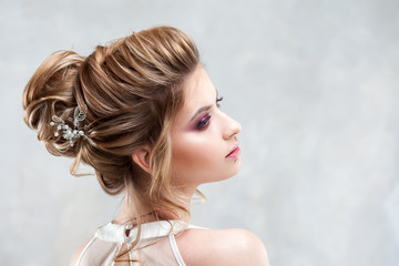 Young beautiful bride with an elegant high hairdo. Wedding hairstyle with the accessory in her hair