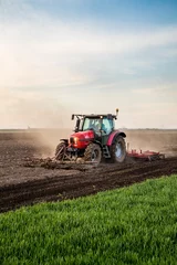 Foto op Plexiglas Tractor Trekker cultiveren veld in de lente