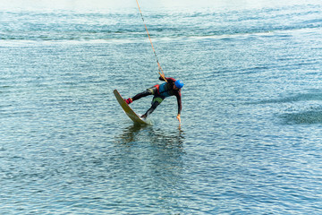 wakeboarder jumps from a springboard behind a rope and makes a wave on the water