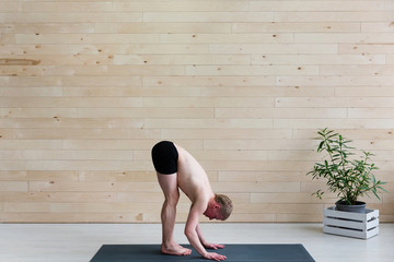 Sporty man practices yoga handstand asana Adho Mukha Vrikshasana at the yoga studio. Balance...