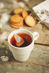 tea brew in a cup (tea bag) on ​​a wooden table and flowering spring twigs. Food background - drink background