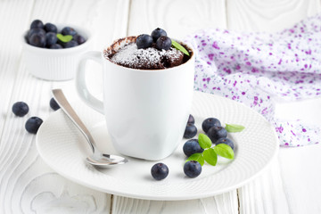 Chocolate cake in a mug with blueberry and powdered sugar