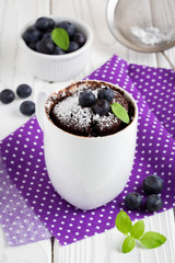 Chocolate cake in a mug with blueberry and powdered sugar
