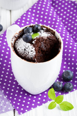Chocolate cake in a mug with blueberry and powdered sugar