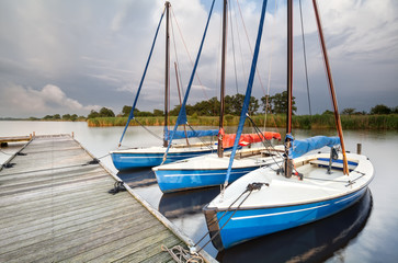 Fototapeta na wymiar blue yachts by pier on big lake