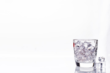 glass with ice cubes on white background
