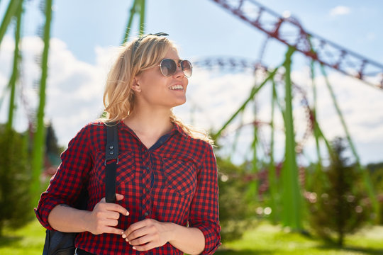 Young pretty blonde deciding what amusement to choose in theme park where she spending weekend or leisure