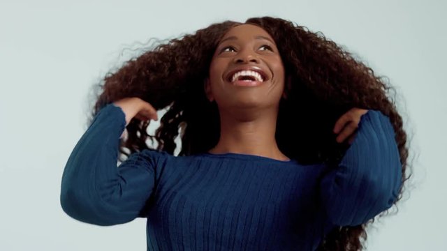 Beauty black mixed race african american woman with long curly hair and laughing. Happy laughing black woman on blue