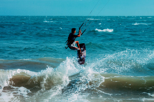Kitesurfer jumping on a beautiful background of spray during the sunset