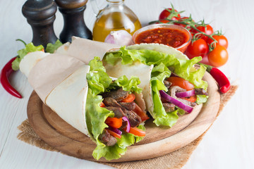 Photo of Mexican sandwich food, burrito, fajita, tacos, wrap made of tortilla, beef, chicken, fresh vegetables on rustic wooden background. Fast food concept. Healthy lunch snack. Copy space. 