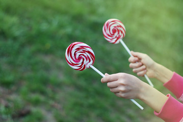 Kid Holding Swirl Colorful Lollipop Isolated over Green blured Garden Copy Paste