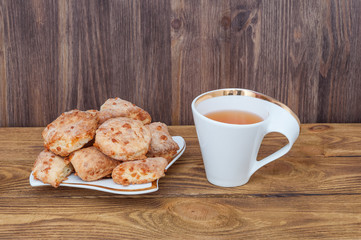 A cup of tea and a plate with homemade cookies on the background of a wooden table.