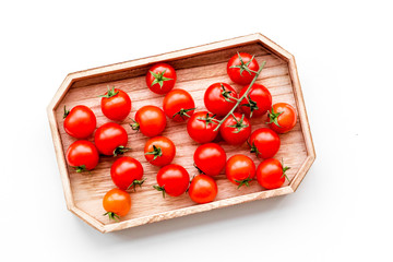 Fresh red cherry tomatoes in wooden tray on white background top view