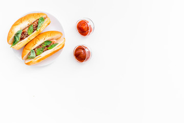 Fastfood concept. Make fresh hotdogs and home. bun for hot dogs with freid sausages and basil near tomato sause on white background top view space for text