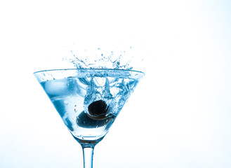 martini in glass with splashes and olives