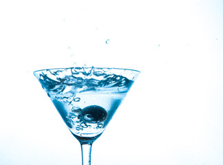 martini in glass with splashes and olives
