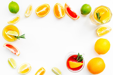Concept of alcoholic cocktail with fruits. Glass with beverage near oranges, grapefruit, lime and rosemary on white background top view copy space