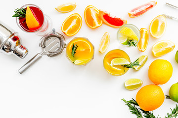 Bartender workplace for make fruit cocktail with alcohol. Shaker, strainer and other bar tools near citrus fruits and glass with cocktail on white background top view copy space