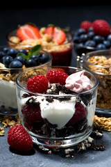various desserts with berries and cream on dark background, closeup vertical