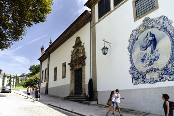 Guimaraes, Portugal. August 14, 2017: Facade of the catholic church called Nossa Senhora do carmo with a mosaic of tiles with the image of the Virgin Mary and tourists strolling