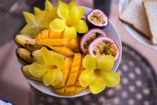 Mango, banana, passion fruit bowl topped with fresh fruit and flowers