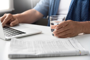 Senior man holding glass of water.