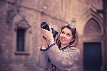 Fototapeta premium Girl holding camera in hands and photographing in the city