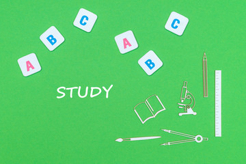 text study, from above wooden minitures school supplies and abc letters on green background