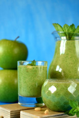Green smoothie in glass vessels on blue background