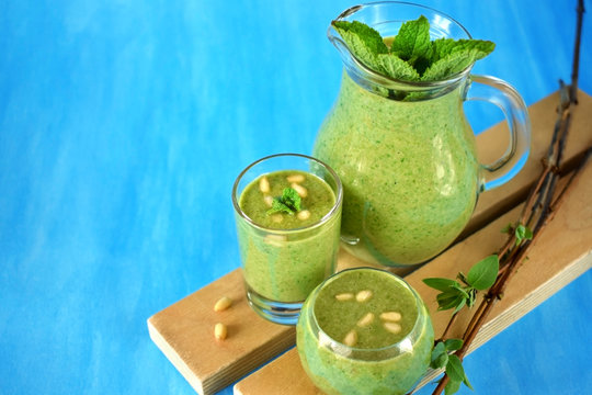 Green smoothie in glass vessels on blue background