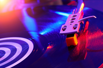 Turntable vinyl record player on the background of a sunset over the lights city. Sound technology...