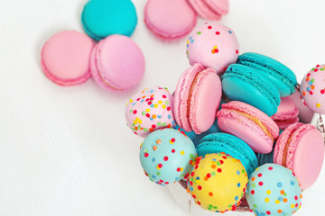 Fototapeta na wymiar Colorful sweet macaroons and cake pops in bowl on wooden white background with copy space. Food for party or dessert. Top view.