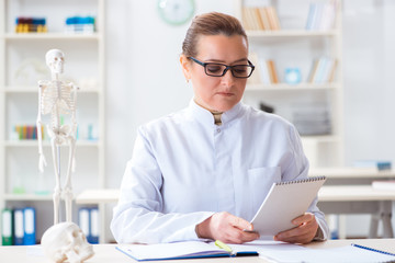 Woman doctor studying human skeleton