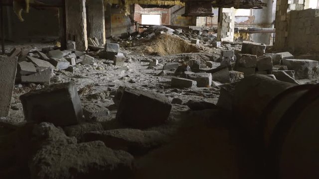 A fictitious person walks through a destroyed building. The floor is strewn with bricks.