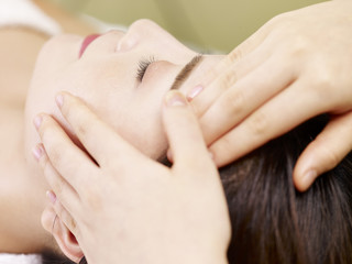 Obraz na płótnie Canvas young asian woman receiving face massage in spa salon