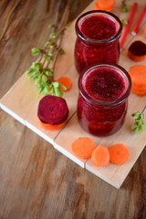Red vegetable smoothie made of carrot and beetroot in glass jars on wooden background