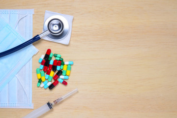 Medication spilling from an open bottle on a wooden background.
