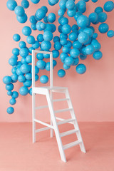 Pink bright studio interior with white ladder and hanging blue balls. Copy space and nobody