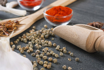 fresh and dried chili fruits, peppercorn, pepper powder, sauce and garlic, bay leaves on old black wooden table background