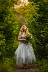 Obraz na płótnie Canvas Beautiful bride in unusual dress with bouquet walking in garden
