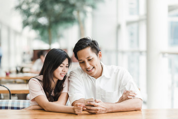Asian couple using smartphone indoor