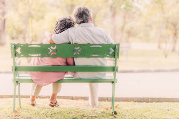senior couple in love sitting on the bench in the park