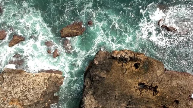 Aerial shot of ocean waves crashing coastline. Portugal