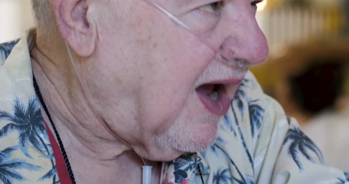 Happy senior man with a supplemental nasal oxygen tube talking passionately