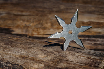 Shuriken (throwing star), traditional japanese ninja cold weapon stuck in wooden background © Sergii