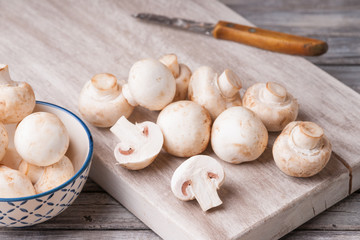 Fresh champignons on a cutting board and in a bowl 
